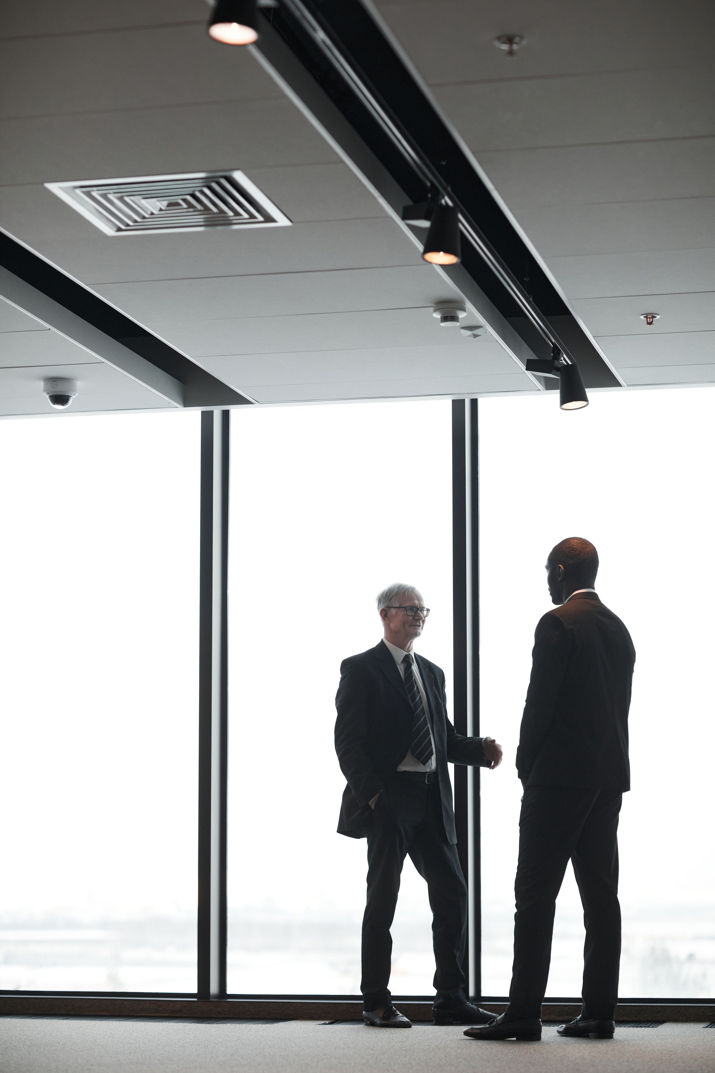 Two executives talking in front of a glass wall